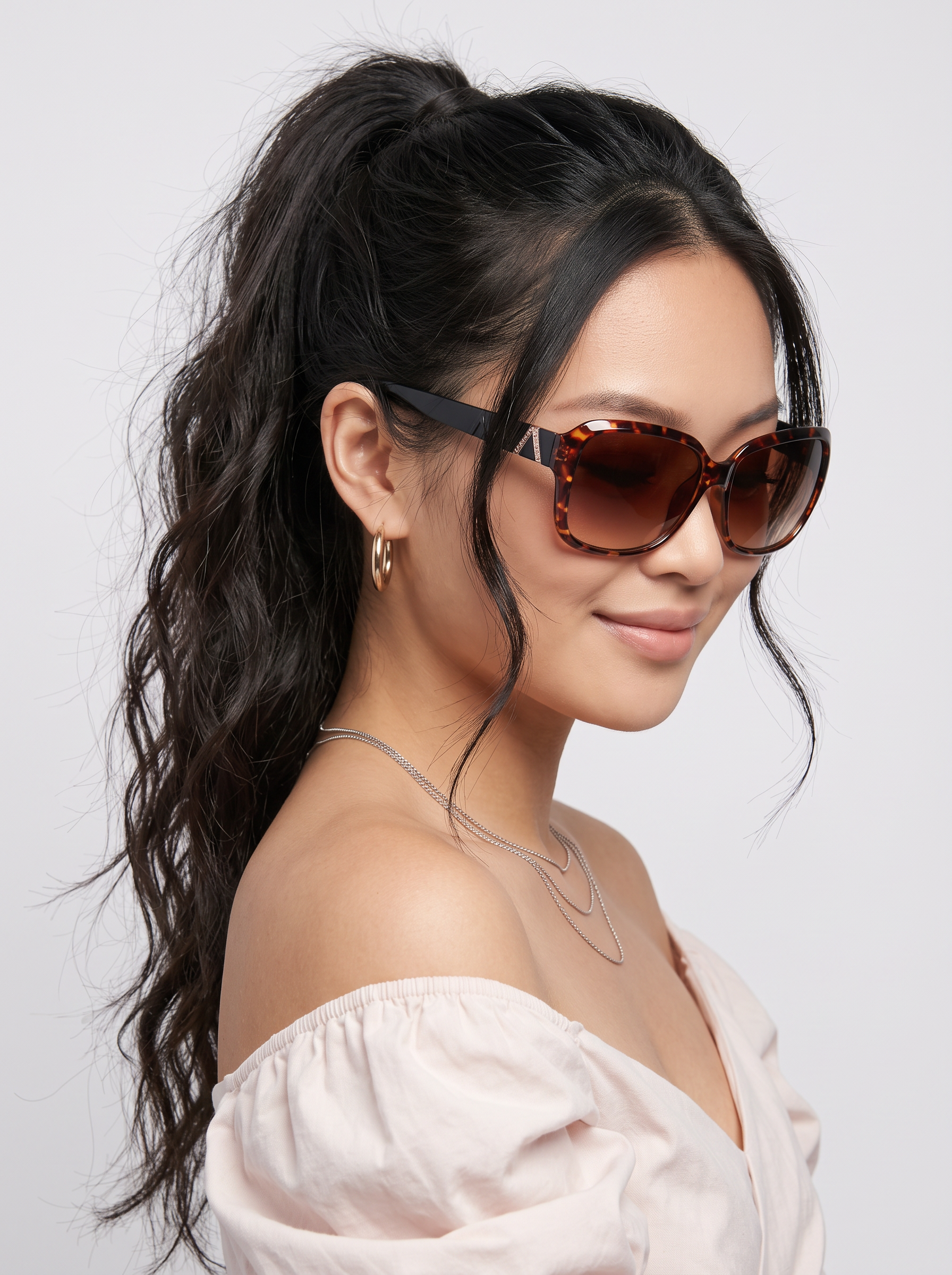 SH6649 Lady - Beachtime Sunglasses Close-up portrait of a woman wearing tortoiseshell oversized sunglasses, with a high ponytail, gold hoop earrings, and a white off-the-shoulder top.