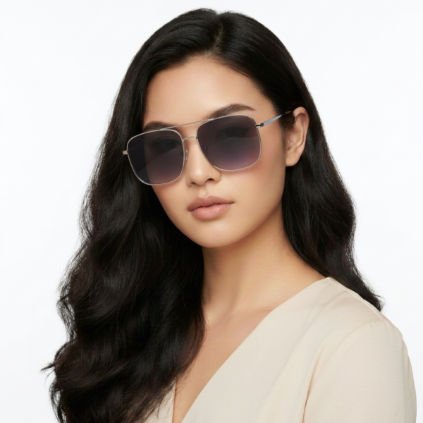 Woman with long dark hair wearing gradient sunglasses and a beige blouse against a white background.