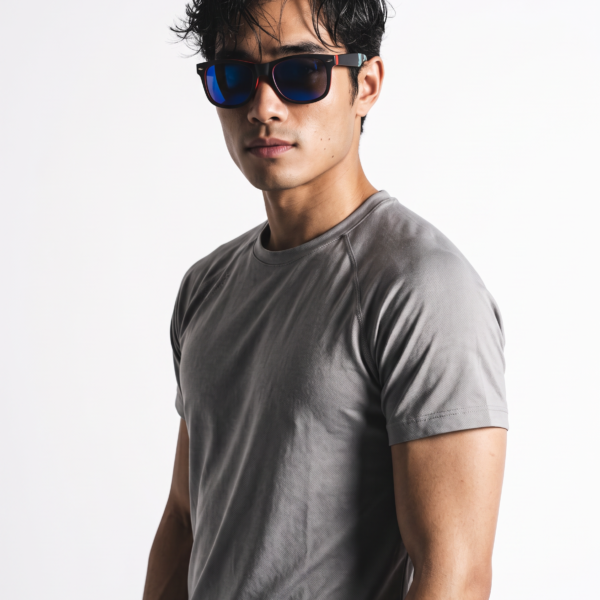 Man wearing blue mirrored sunglasses and a gray athletic T‑shirt, posed against a white studio background.