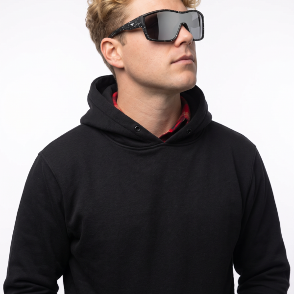 Person with curly blond hair wearing oversized black sunglasses and a black hoodie, looking to the right.