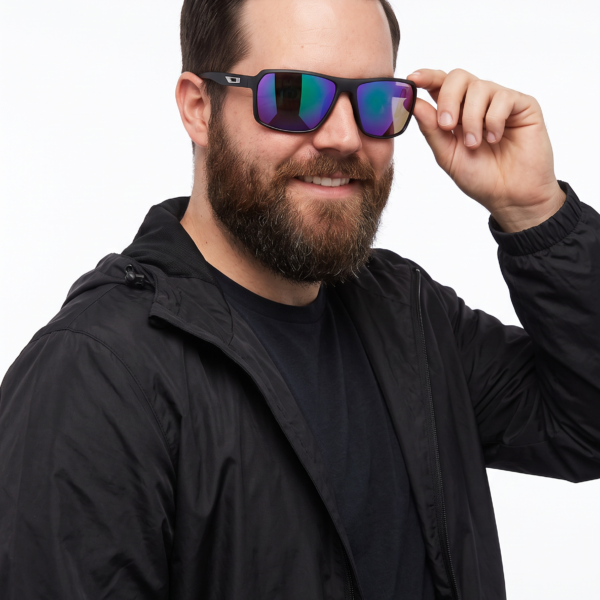 Man in a black jacket wearing reflective wraparound sunglasses, adjusting the frame with his right hand against a white background